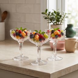 Three clear glass coupe glasses with textured bowls and starburst bases on a white background - view 1