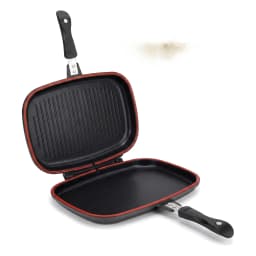 Open black granite double-sided grill pan with red trim, cooking grilled chicken, asparagus, and tomatoes on a kitchen count… - view 2