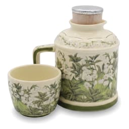 Cream porcelain jug with green floral pattern and matching cup inverted on top, on a kitchen counter. - view 5