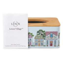Rectangular light blue metal tissue box with colorful house design and natural wood top, on a wooden coffee table. - view 2