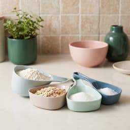 Set of 4 plastic measuring cups and spoons in light blue, beige, mint green, and dark blue on a white background. - view 1