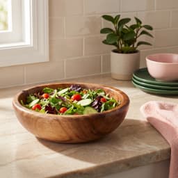 Round natural brown wooden serving bowl filled with fresh green salad on a light marble kitchen counter - view 3