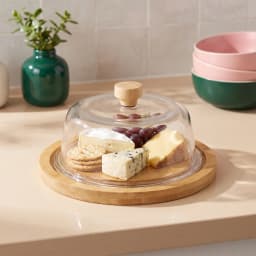 Round mini serving cloche with a clear glass dome and a light brown wooden base and knob on a white background. - view 1