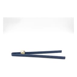 Single dark blue silicone kitchen tongs with a small white tag, lying on a white shelf. - view 2