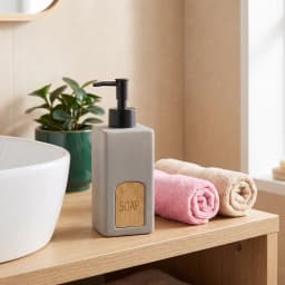 Single grey ceramic soap dispenser with a black plastic pump and a light wooden label engraved with 'SOAP' on a wooden vanit… - view 1