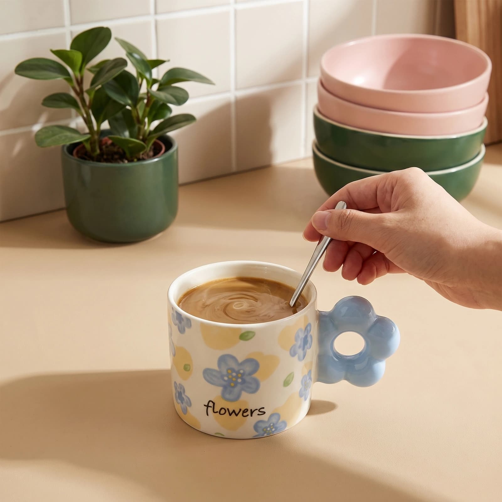 Cream ceramic mug with light blue floral pattern and a unique light blue flower-shaped handle on a white shelf.