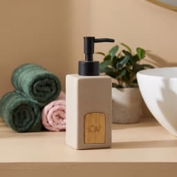 Beige speckled ceramic soap dispenser with square body, black plastic pump, and a light wood-look label saying 'SOAP'. - view 1