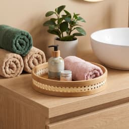 Set of three round natural light brown bamboo serving trays stacked, with perforated decorative rims on a white background. - view 5