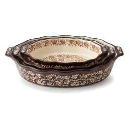 Three nested oval porcelain baking dishes with black floral patterns on a dark background and cream interior. - view 2