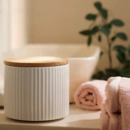 White ribbed porcelain storage jar with a wooden lid and scoop, filled with coffee beans on a kitchen counter. - view 4
