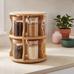 Light brown bamboo rotating two-tier stand holding six clear glass jars with light brown bamboo lids on a white surface. - view 1