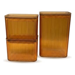 Three amber ribbed acrylic storage containers with square lids, filled with pasta and nuts, on a kitchen counter. - view 2