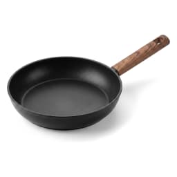 Black granite frying pan with a wooden handle on a gas stove, cooking green asparagus and cherry tomatoes. - view 2