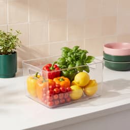 Clear rectangular acrylic storage bin with integrated handles and ribbed bottom, placed on a white shelf. - view 1