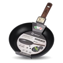 Black granite frying pan with a wooden handle on a gas stove, cooking green asparagus and cherry tomatoes. - view 3