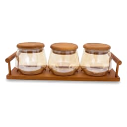 Three clear glass storage jars with round light brown wood lids, sitting on a rectangular dark brown wood tray with handles,… - view 3