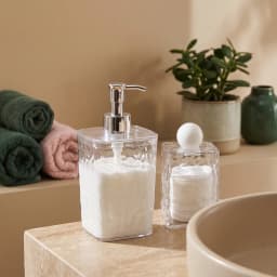 Two clear textured plastic bathroom accessories: a soap dispenser with a silver pump and a lidded container with a white sph… - view 1