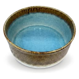 Round porcelain bowl with blue reactive glaze interior and brown and green textured exterior on a white background. - view 5