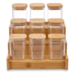 Nine clear square glass storage jars with light wood lids on a matching tiered wooden stand, displayed against a plain light… - view 2
