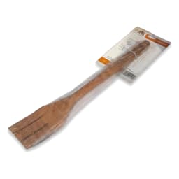 Single brown wooden slotted cooking fork in clear plastic packaging, lying on a white surface in a store shelf. - view 2