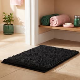Top-down view of a rectangular black runner mat with a soft, textured bobble-like fabric surface on a white background. - view 1