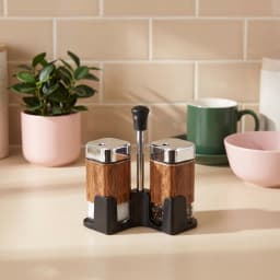 Two square glass salt and pepper shakers with wood-look wrap, chrome tops, and a black stand on a white background. - view 1