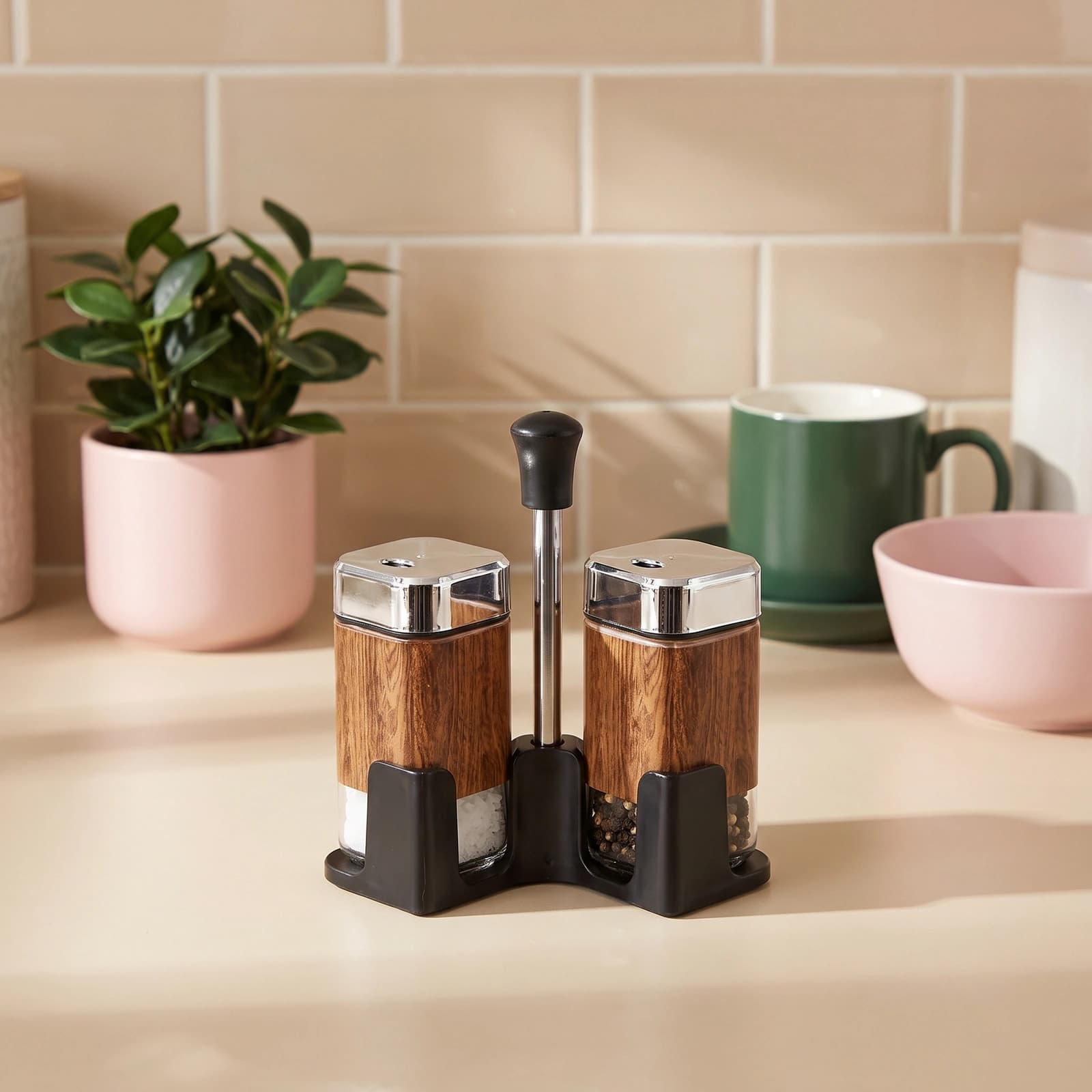 Two square glass salt and pepper shakers with wood-look wrap, chrome tops, and a black stand on a white background.