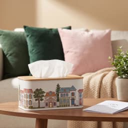 White rectangular metal tissue box with a light brown wooden lid, decorated with a colorful village street scene. - view 1