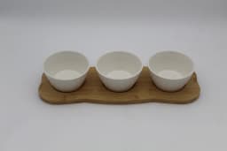 Three white porcelain serving bowls with embossed patterns on a light brown wooden tray, isolated on white. - view 2