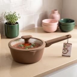 Brown ceramic saucepan with a beige interior and a clear glass lid, featuring a matching brown handle, on a white background. - view 1