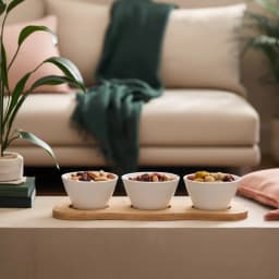 Three white porcelain serving bowls with embossed patterns on a light brown wooden tray, isolated on white. - view 1