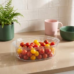 Single clear oval acrylic serving dish with a textured bottom, placed on a white shelf. - view 1