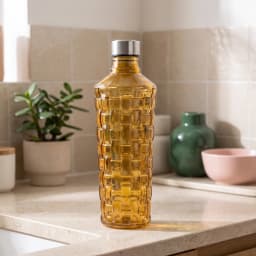 Single amber glass bottle with a textured, basket-weave pattern and a silver cap, standing on a white shelf. - view 1