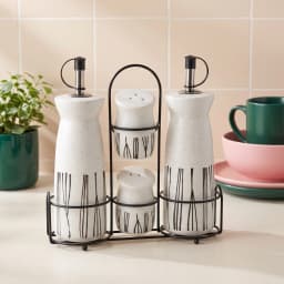 Cream porcelain oil and vinegar dispensers with two matching salt and pepper shakers in a black metal stand, black vertical… - view 1