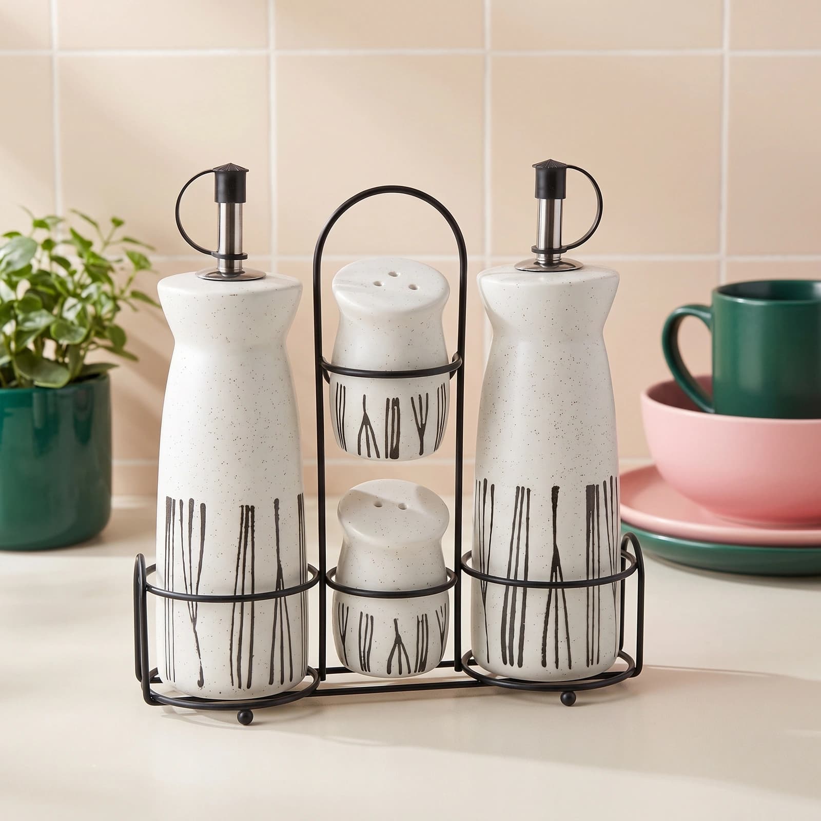 Cream porcelain oil and vinegar dispensers with two matching salt and pepper shakers in a black metal stand, black vertical…