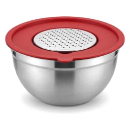 Stainless steel mixing bowl with red whisk and red lid on a light kitchen counter, next to a pink potted plant. - view 4