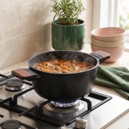 Black ceramic casserole pot with wood-look handles and lid, 22cm diameter, shown in packaging. - view 4