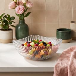 Single clear glass serving bowl with a wavy, ribbed texture on a white background, viewed from a slight angle. - view 1