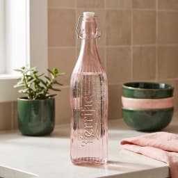 Tall pink ribbed glass bottle with a white swing top closure on a white background, showing the word 'Terrific' embossed. - view 1