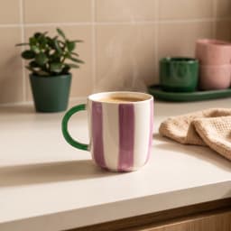 Cream ceramic mug with vertical purple stripes and a bright green handle on a white background - view 1