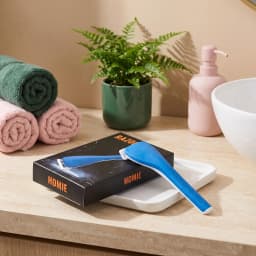 Blue and white women's razor with an ergonomic handle and white blades, against a dark background with text. - view 1