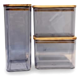 Three dark grey acrylic rectangular storage containers with light brown wooden lids on a white shelf. - view 2