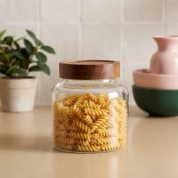 Clear glass storage jar with a dark brown wooden lid on a white background, front view - view 1