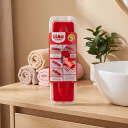 Red plastic rotatable mop head refill with white microfiber pad in packaging, on a wooden surface. - view 1