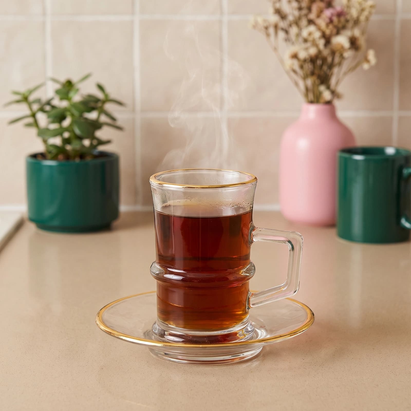 Clear glass mug with a handle and matching round glass saucer, both featuring a delicate gold rim, on a white background.