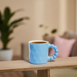 Single light blue ceramic mug with a unique handle made of connected spherical shapes, on a white background. - view 4
