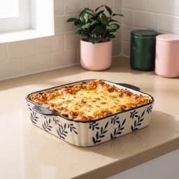 Rectangular porcelain baking dish, cream with navy blue leaf pattern and fluted sides, on a white background. - view 1