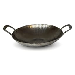 Hammered gray metal wok with two handles, filled with colorful stir-fried chicken and vegetables, on a light kitchen counter. - view 2