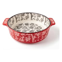 Red granite oval baking dish with white floral patterns, filled with baked macaroni and cheese, on a kitchen counter. - view 2