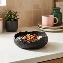 Single black porcelain serving bowl with a textured exterior and an irregular, wavy rim on a white background. - view 5